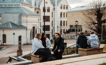 en gruppe mennesker som sitter på en benk foran en bygning