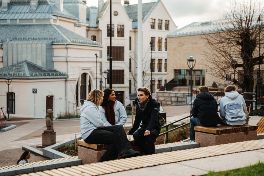 en gruppe mennesker som sitter på en benk foran en bygning